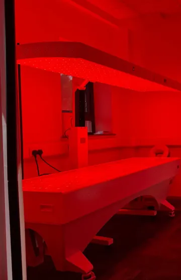 The full-body red light bed glowing in its private room at the Harlow clinic